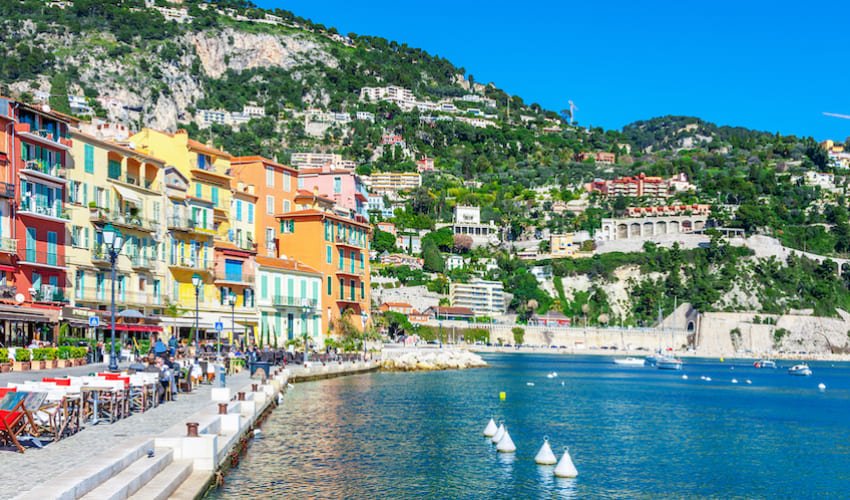 Le port de Nice, ses façades colorées et ses collines arborées.