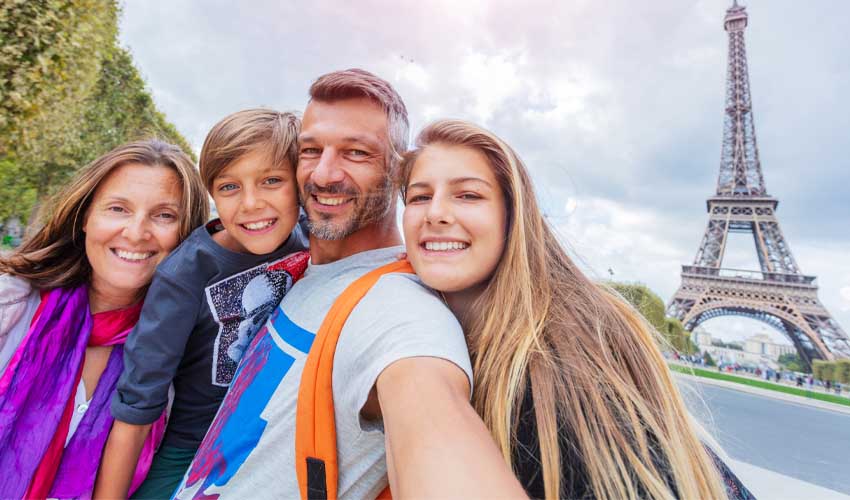 Une famille heureuse prenant un selfie à côté de la Tour Eiffel
