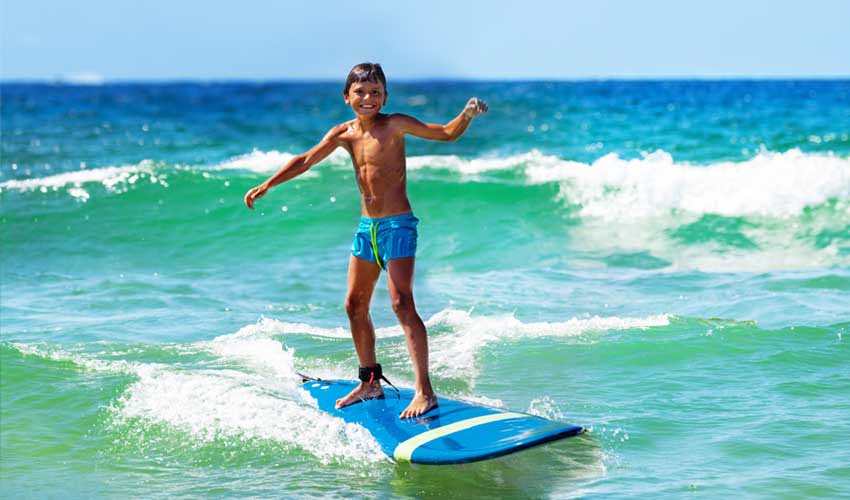 Sport nautique : enfant qui fait du surf depuis un village vacances