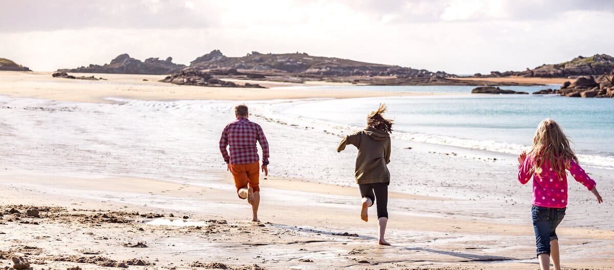 Une famille en vacances en Bretagne court sur la plage.