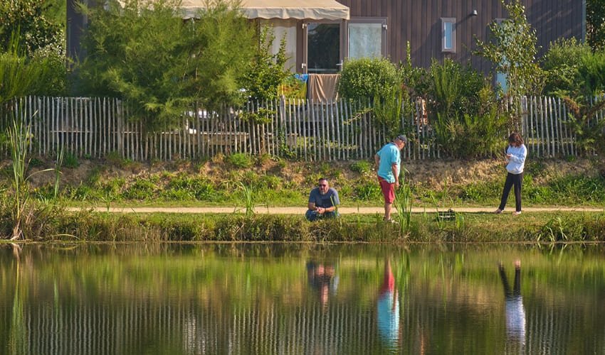 Des personnes pêchent à proximité d'un bungalow du Domaine d’Inly à Penestin.