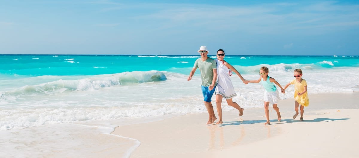 Une famille en vacances marche sur un plage par beau temps.