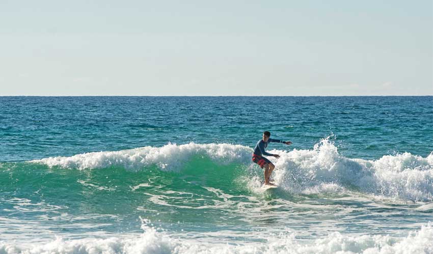 Jeune homme faisant du surf sur la plage à Biscarosse, dans le sud de la France 