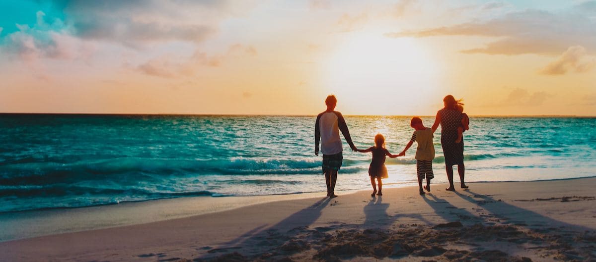 Une famille admire le coucher de soleil sur une plage de Charente-Maritime.