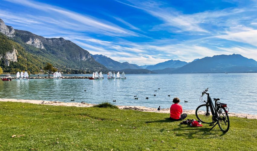 Une cycliste fait une pause en admirant le lac d’Annecy